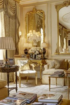 a living room filled with furniture and a chandelier above a table in front of a mirror