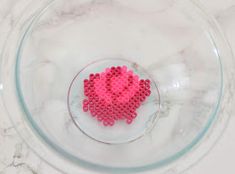 a pink heart in a glass bowl on a marble table