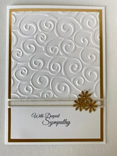 a white card with gold accents and a flower on the front, which reads well done sympathy