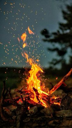 the fire is burning brightly in the night sky with lots of sparks coming from it