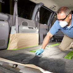 a man in blue shirt and white gloves waxing the interior of a vehicle with green tape