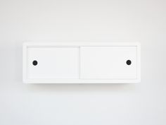 a white cabinet with two black knobs on the front and one is closed up