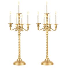 two gold candelabras with candles on them