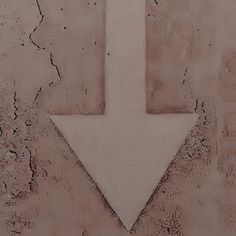 a white arrow painted on the side of a concrete wall with peeling paint and chipped edges