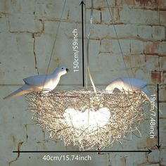 two white birds sitting on top of a nest in the middle of a brick wall