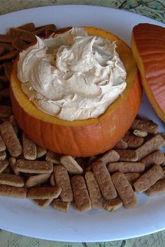 a white plate topped with pumpkins and crackers next to a bowl of whipped cream