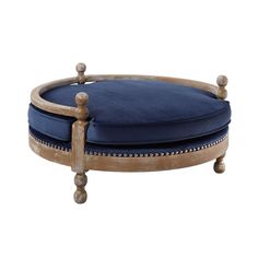 an upholstered wooden ottoman with blue velvet cushion