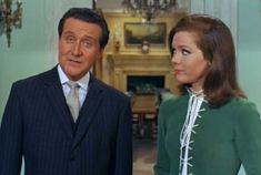 a man in a suit and tie standing next to a woman wearing a green dress