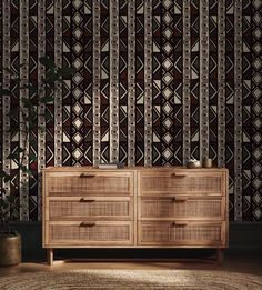 a large wooden dresser sitting in front of a wallpapered wall with geometric designs on it