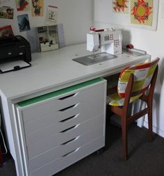 a sewing machine sitting on top of a white desk next to a chair and printer