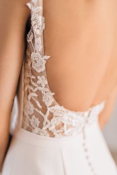 the back of a woman's dress with white lace on it and buttons at the bottom