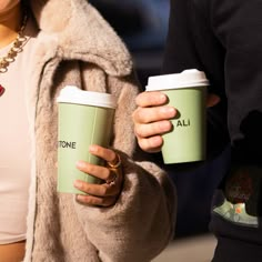 two people holding coffee cups in their hands