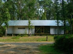 an old barn sits in the middle of a wooded area with trees and grass around it