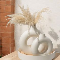 two white vases sitting on top of a wooden table