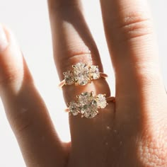 a woman's hand with three diamond rings on top of her ring, and the middle finger is holding an engagement ring