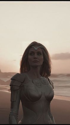 a woman standing on top of a beach next to the ocean in a body suit