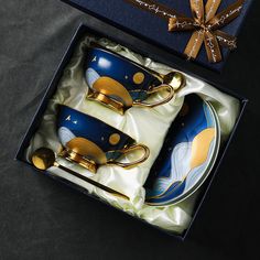 two blue and gold tea cups in a gift box