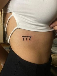 a woman's stomach with the number seven tattoo on her lower back and side