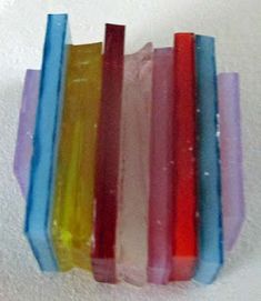 five different colored candles sitting on top of each other in plastic wrapper bags with white background