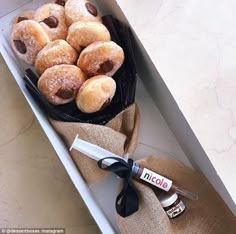 a box filled with powdered donuts next to a bottle of boojute