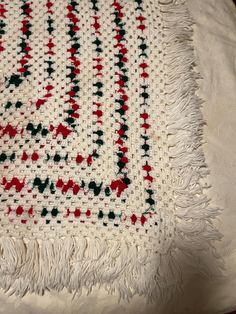 a white blanket with red, green and black designs on it sitting on a table