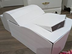 an open box sitting on top of a wooden floor next to a white bed frame