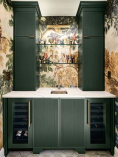 a kitchen with green cabinetry and wallpaper on the walls, along with a marble counter top