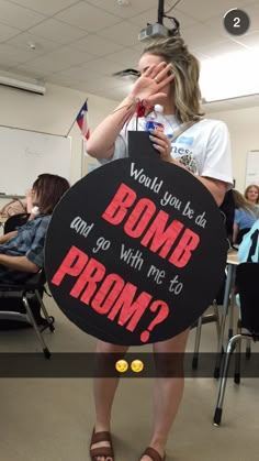 a woman holding a sign that says, would you be at bomb with me to prom?