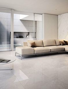 a modern living room with marble flooring and white walls, along with a large sectional sofa