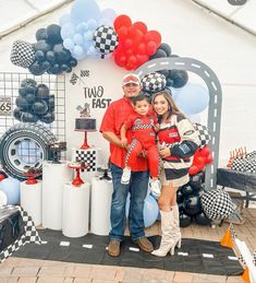 a man and woman holding a child in front of a race themed backdrop