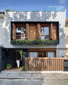 a woman is standing in the doorway of a modern house with wooden shutters and balconies