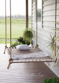 a porch swing with pillows and plants on it