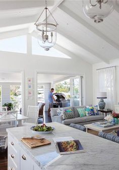 a living room filled with furniture next to a kitchen and breakfast nook in front of a large window