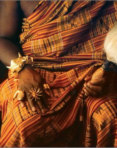 a woman in an orange and yellow dress with her hands on her belly