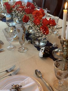 the table is set with silverware and red roses