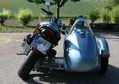 a blue motorcycle with a side car parked on the street in front of a tree