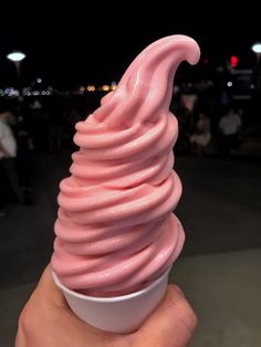 a hand holding up a pink ice cream cone