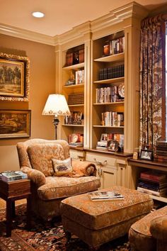 a living room filled with furniture and bookshelves next to a window covered in curtains