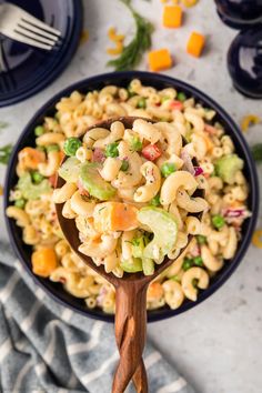 a wooden spoon filled with pasta salad on top of a table