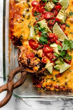 a casserole dish with tomatoes, avocado and other toppings