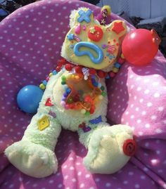 a teddy bear with a birthday cake on it's head sitting in a chair