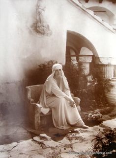 an old black and white photo of a woman sitting on a bench