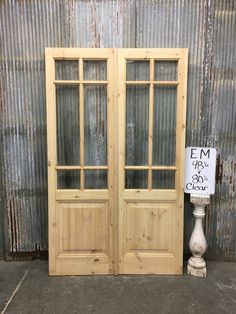 two wooden doors sitting next to each other in front of a metal wall with a sign on it