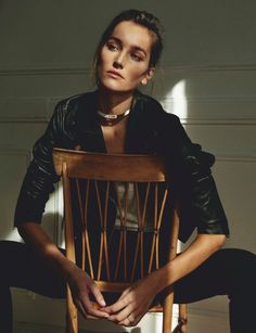 a woman sitting in a wooden chair with her hands on the back of the chair