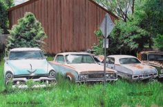 three old cars parked in front of a barn