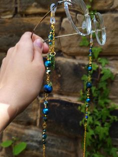 a hand holding a pair of glasses with beads attached to it