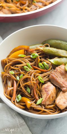 two bowls filled with noodles, meat and veggies on top of a table