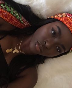 a woman laying on top of a bed wearing a headband and necklace with her eyes closed