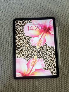 a leopard print with pink flowers on the cover of a tablet computer case, sitting on a carpeted surface