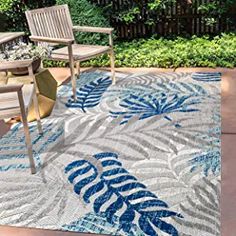 a blue and white area rug sitting on top of a patio next to two chairs